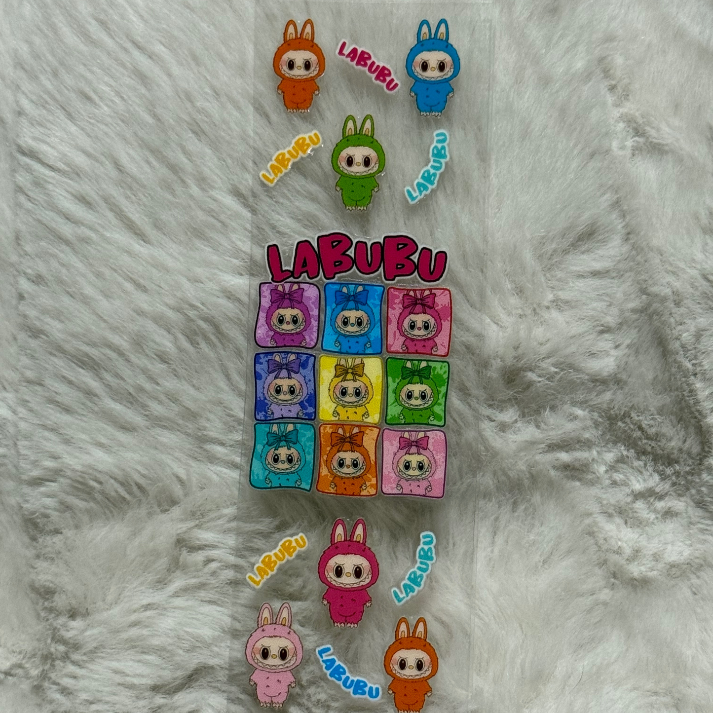 A clear adhesive pen wrap featuring colorful Labubu character illustrations and text.