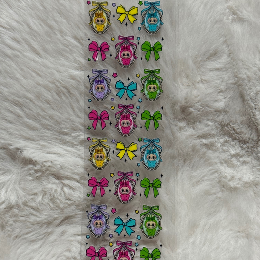 A clear adhesive pen wrap featuring a repeating pattern of colorful bows and framed baby characters.