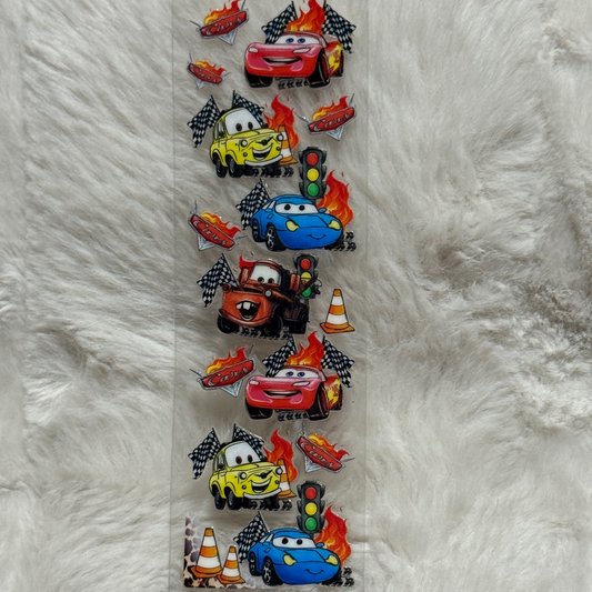 A vertical strip of UV DTF adhesive decals featuring cartoon race cars, flames, and traffic cones.
