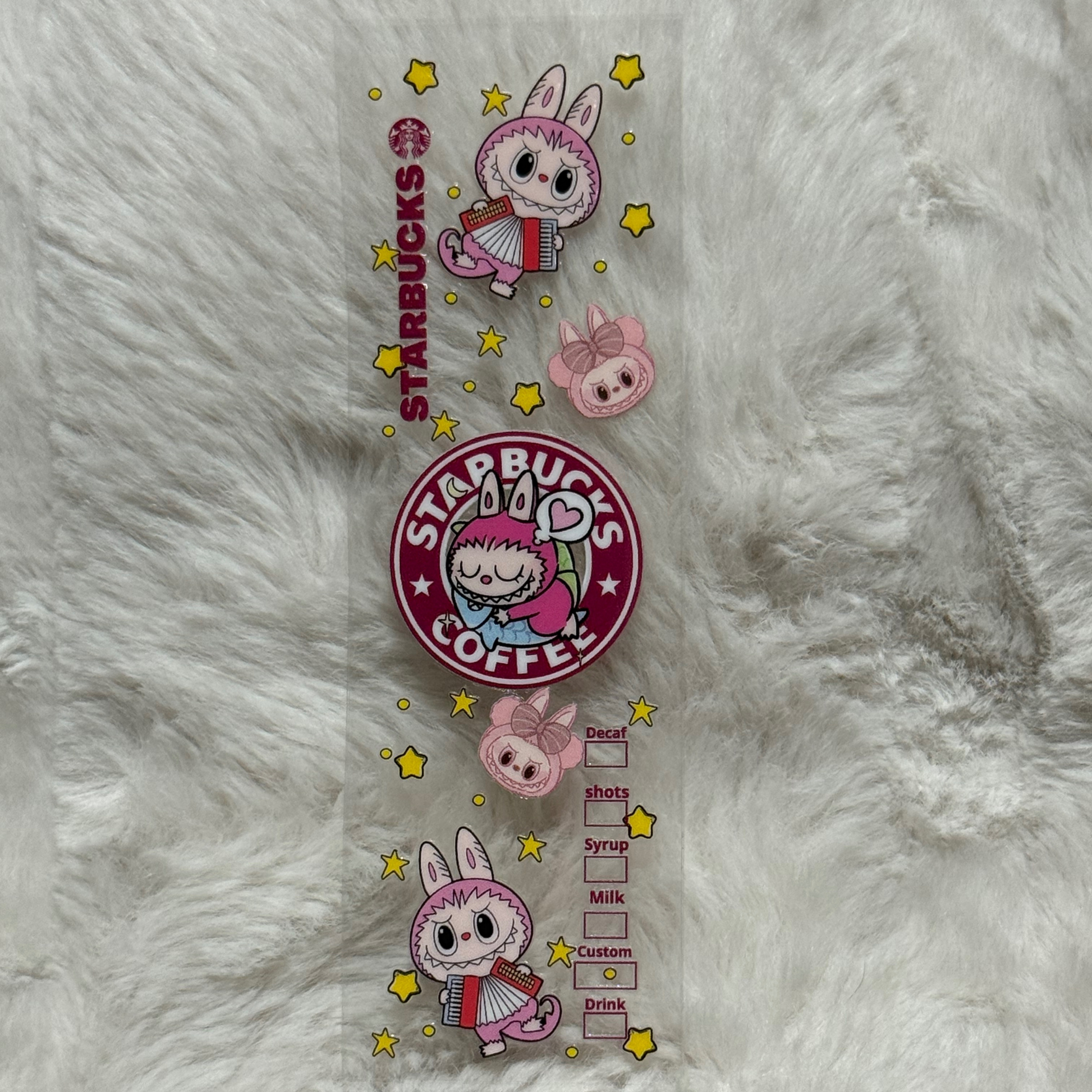 A clear UV DTF pen wrap featuring pink bunny characters, stars, and a Starbucks logo design.