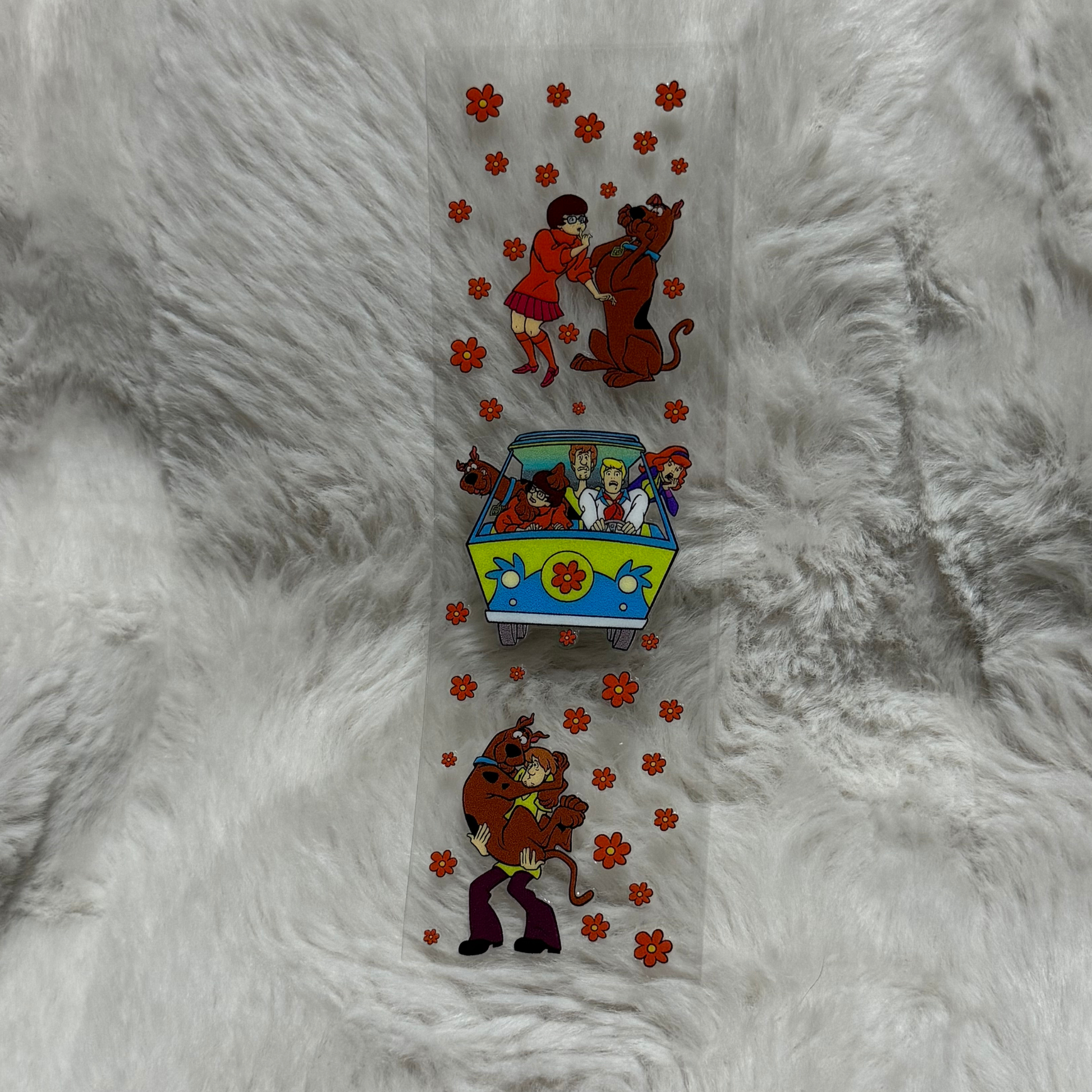 A clear adhesive pen wrap featuring Scooby-Doo characters and orange flowers on a white background.