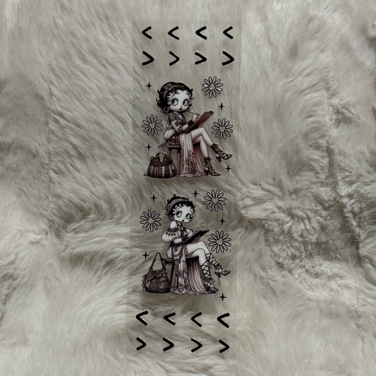 A clear adhesive pen wrap featuring two illustrations of Betty Boop sketching with floral accents.