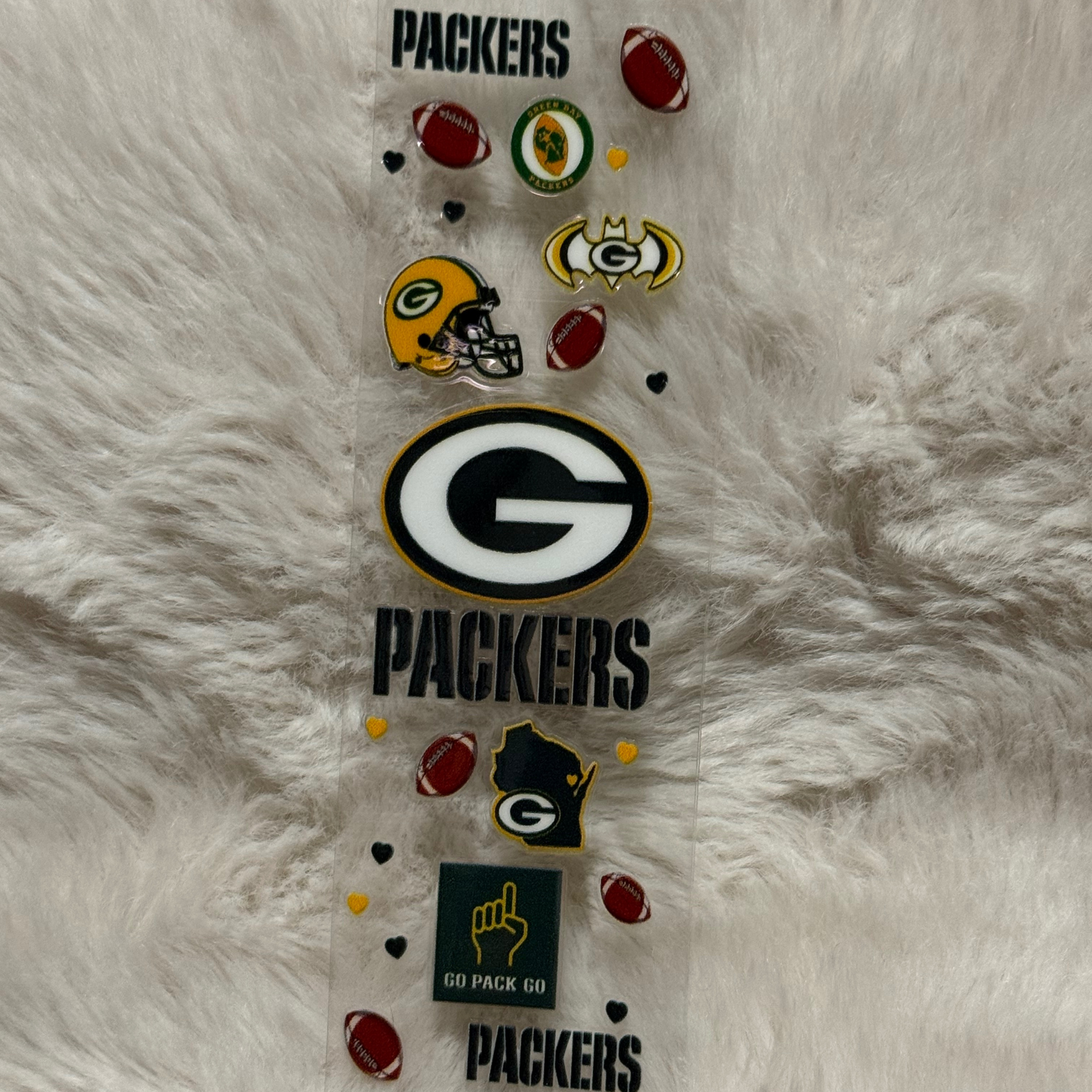 A Green Bay Packers themed UV DTF adhesive pen wrap featuring team logos and football icons.