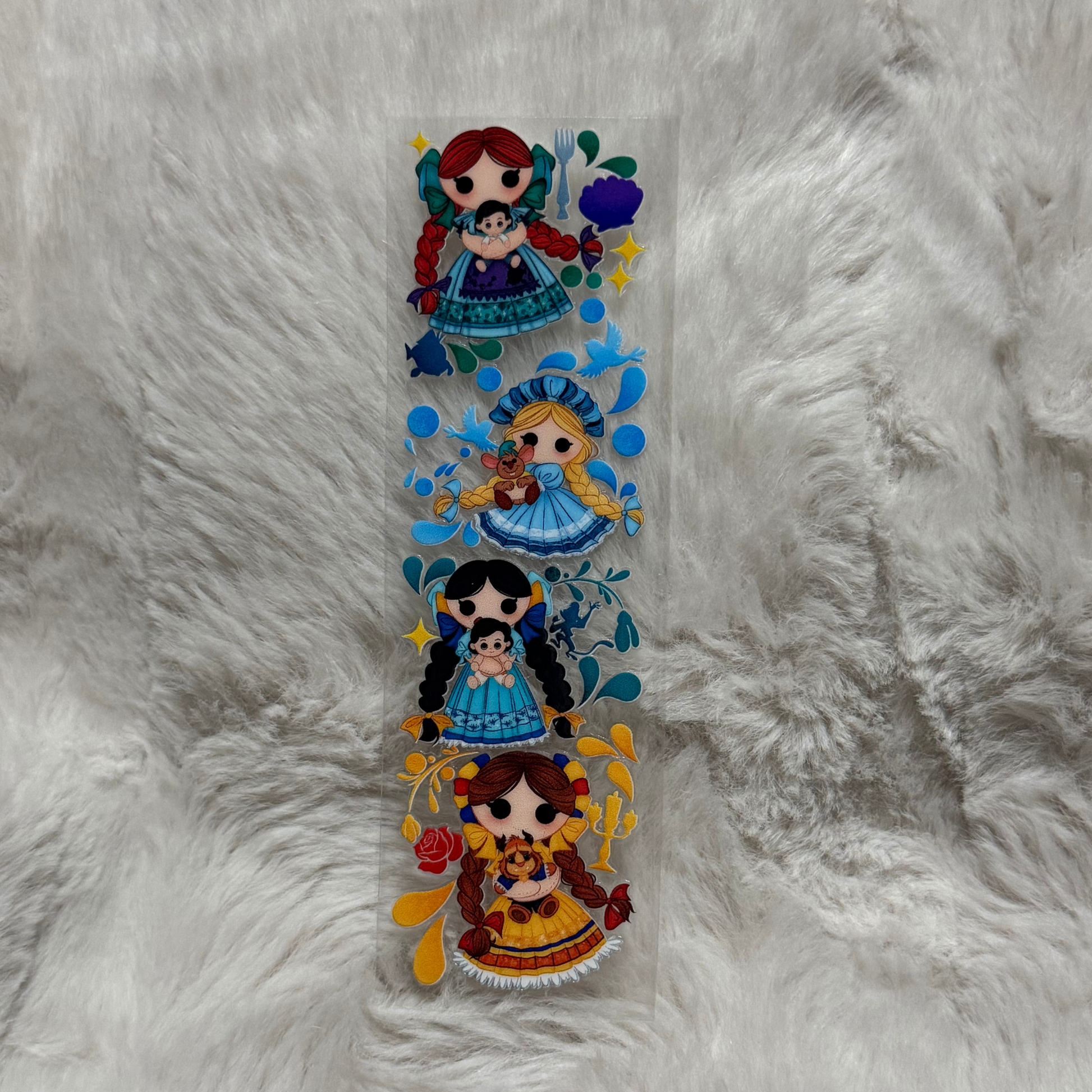 A UV DTF adhesive pen wrap featuring four illustrated dolls with braided hair on a clear sheet.
