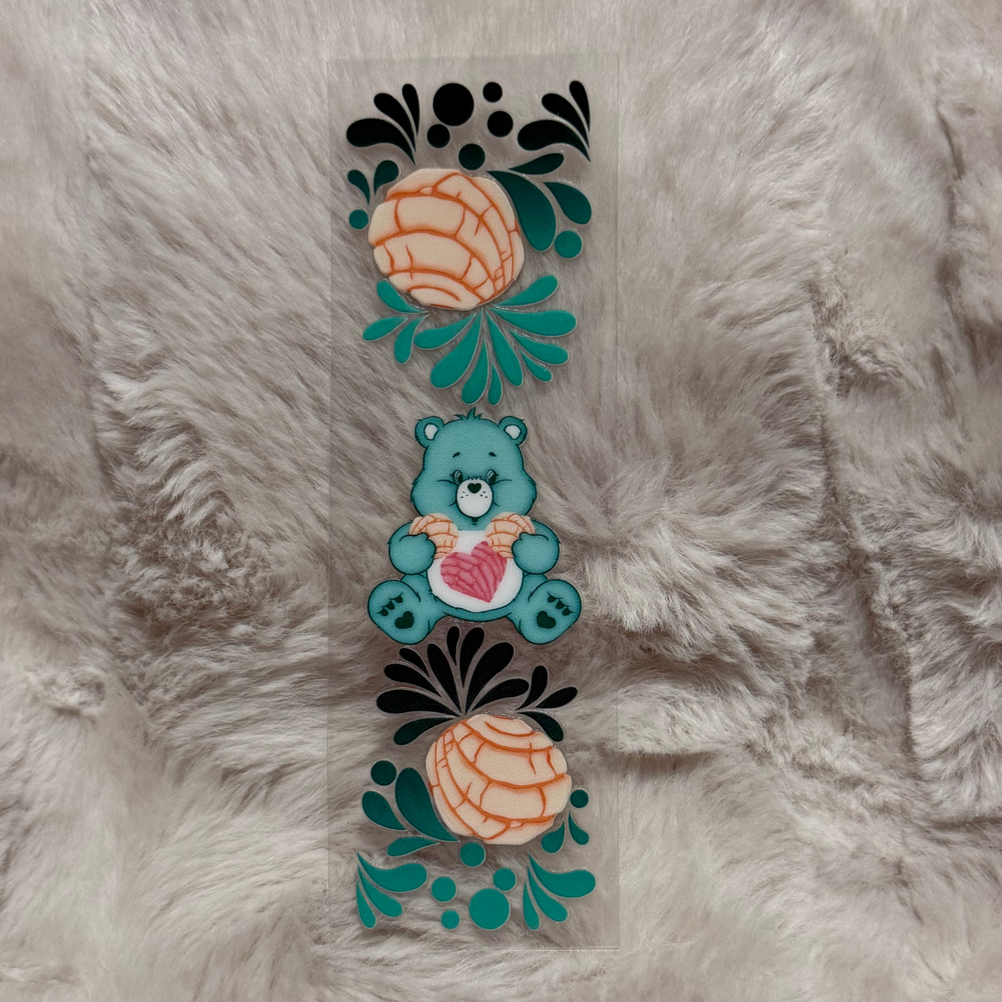A rectangular UV DTF pen wrap featuring a teal bear holding a heart between two concha pastries.
