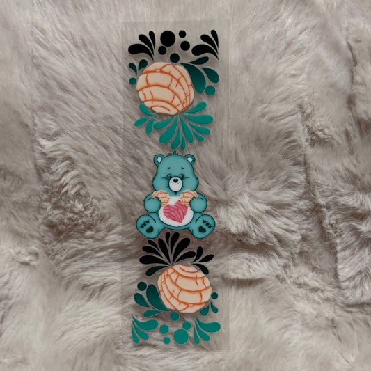 A rectangular UV DTF pen wrap featuring a teal bear holding a heart between two concha pastries.