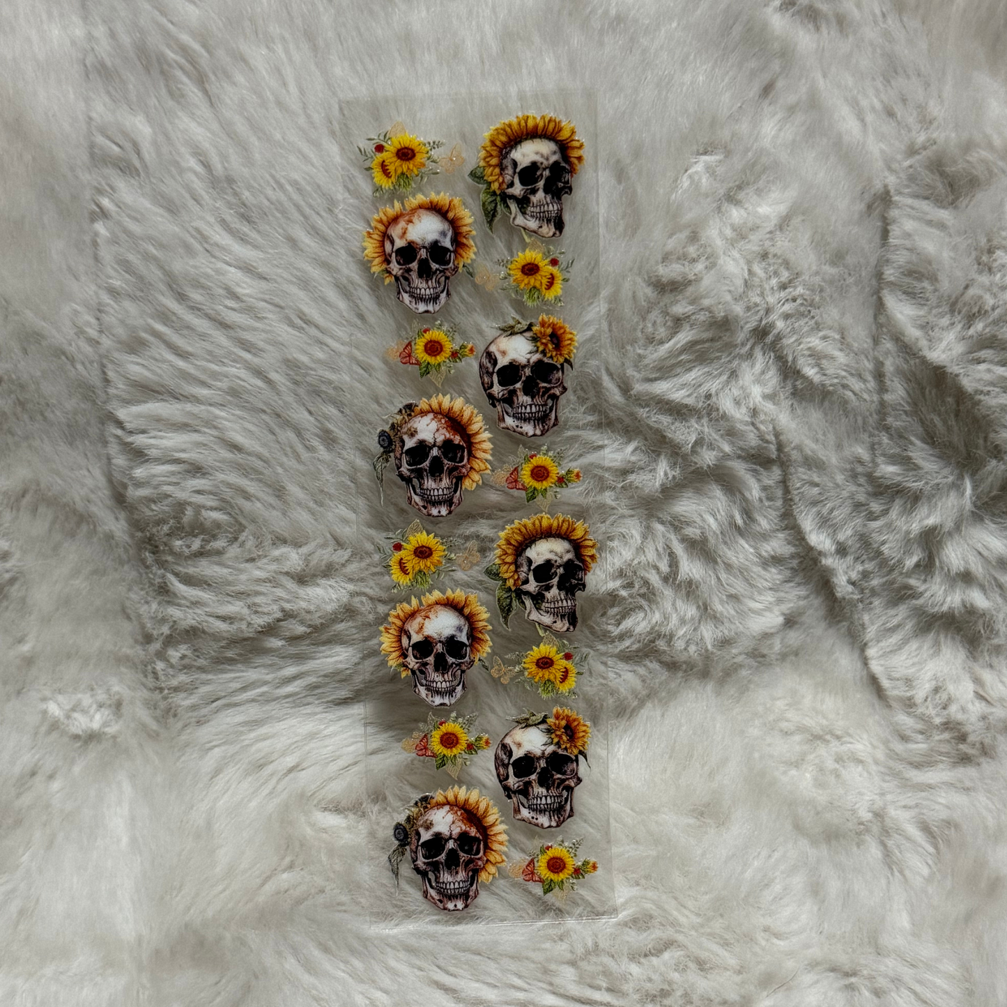 A rectangular sheet of UV DTF decals featuring skulls adorned with sunflowers.