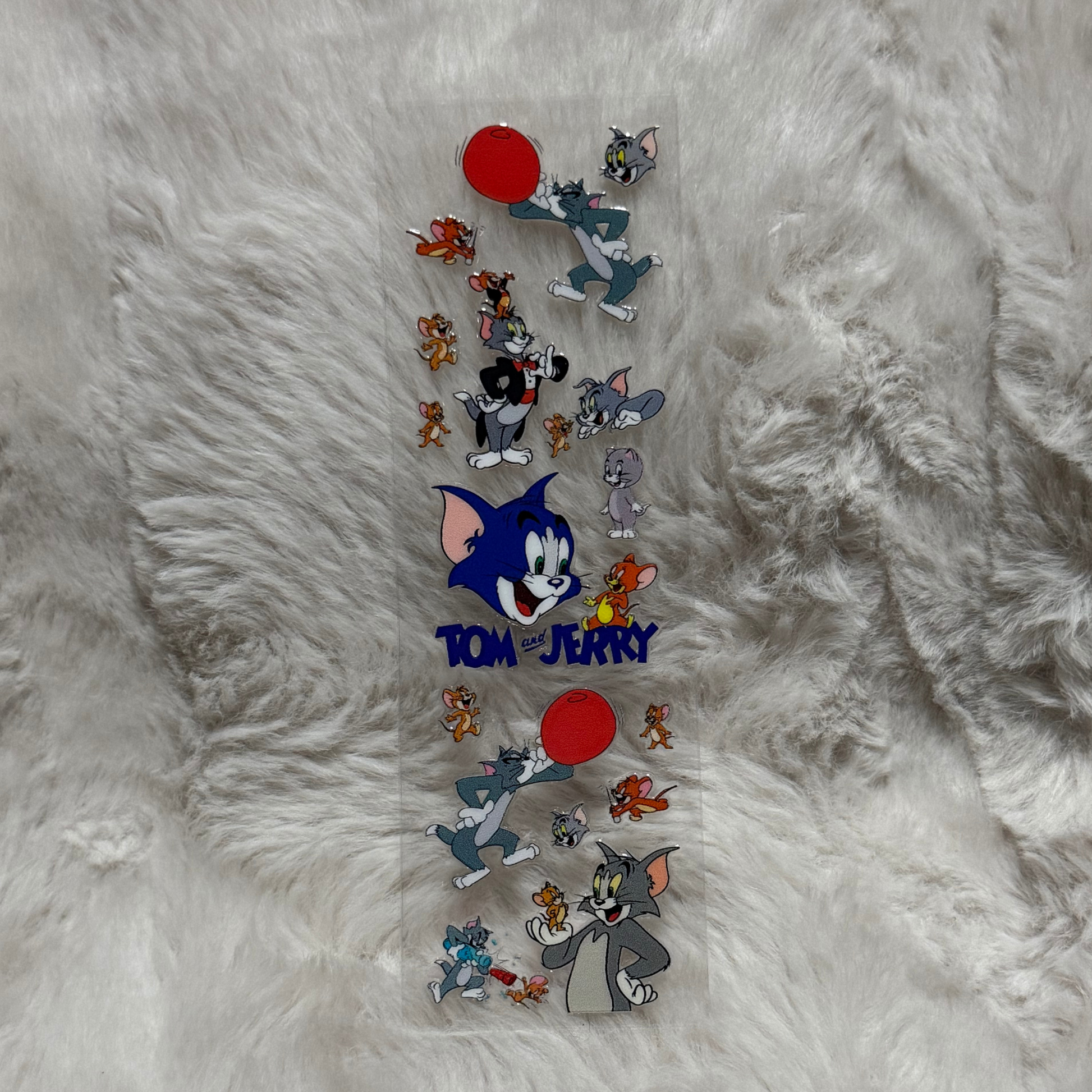 A clear adhesive pen wrap featuring various Tom and Jerry character illustrations.