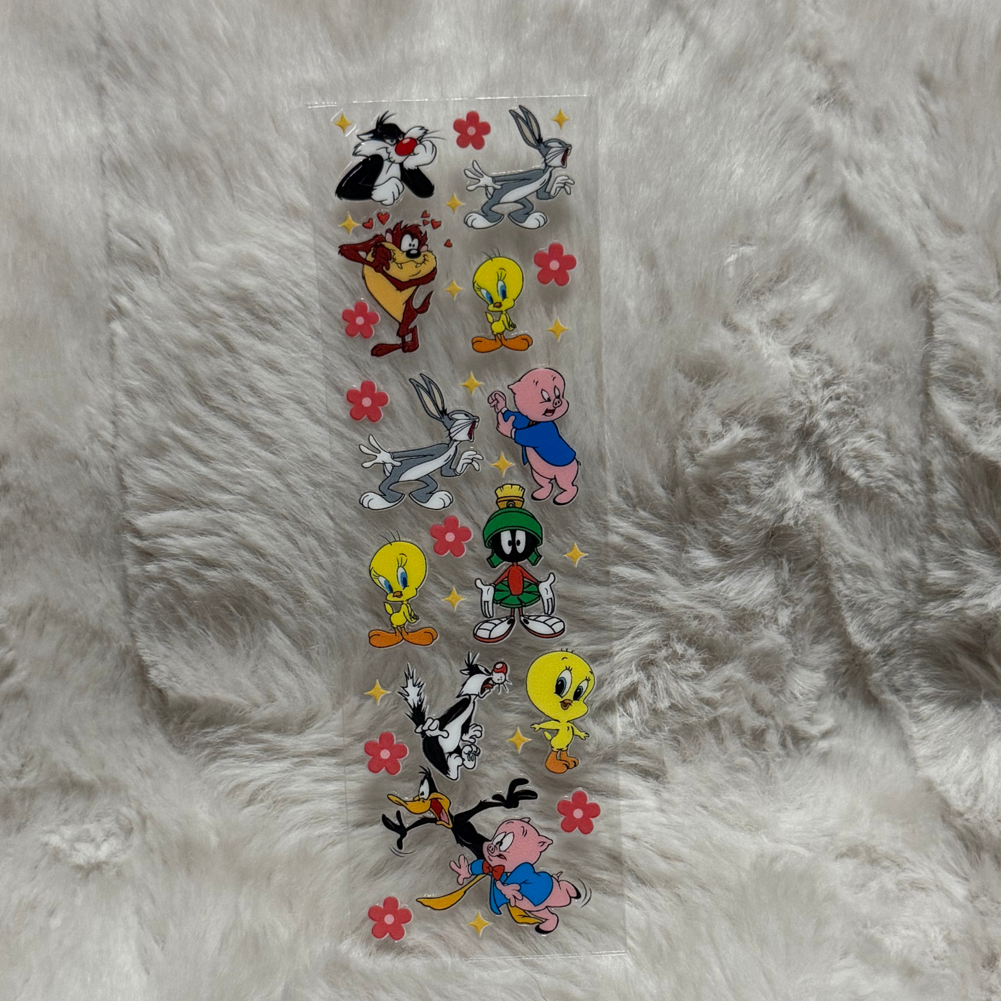 A clear adhesive sheet featuring various Looney Tunes characters and small red flowers.