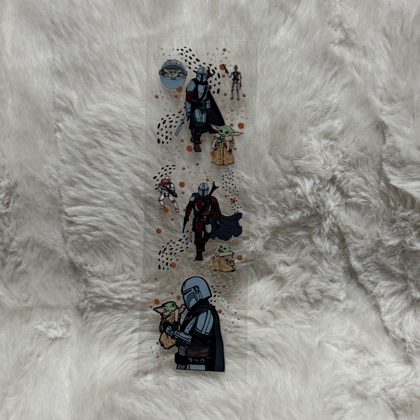 A clear UV DTF pen wrap featuring The Mandalorian and Grogu on a white faux fur background.