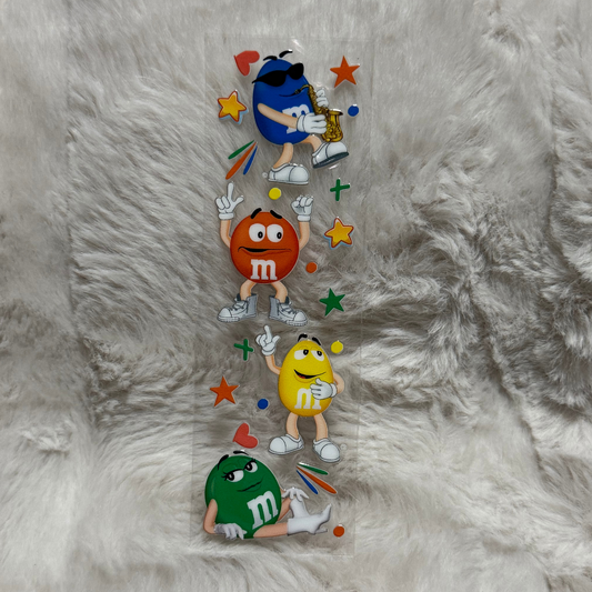A vertical UV DTF decal featuring four M&M characters with colorful stars and shapes.